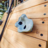 Close-up of a moulded climbing hold bolted to the cedar rock wall of the Canyon Creek swing set
